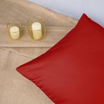 Poszewka satynowa 50x60 w kolorze głębokiej czerwieni, rozłożona na jasnym tle. Produkt leży na gładkiej powierzchni, obok dwóch szklanych świeczników. Widoczna tekstura tkaniny, matowa i delikatna. Brak dodatkowych napisów lub logo.