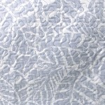 Narzuta drukowana Remo 170x210 w odcieniach niebieskiego, z subtelnym, geometrycznym wzorem. Ułożona na płasko, z widoczną, teksturowaną powierzchnią. Idealna do zastosowania jako dekoracja sypialni lub salonu.