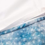 Pościel satyna bawełniana 160x200 Luxury Premium Belize w kolorze niebieskim z białymi kropkami, rozłożona z widocznym zamkiem błyskawicznym. Górna poszwa jest biała, natomiast dolna ma morski wzór. Zbliżenie na szczegóły tkaniny i zamek.