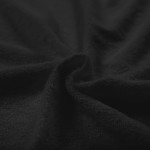 Czarna pościel frotte 200x220 o teksturowanej powierzchni, ułożona w złożony sposób, ukazująca miękką fakturę materiału. Zdjęcie z bliska, akcentujące detale tkaniny. Tło proste, ciemne, pozwala skupić się na strukturze.