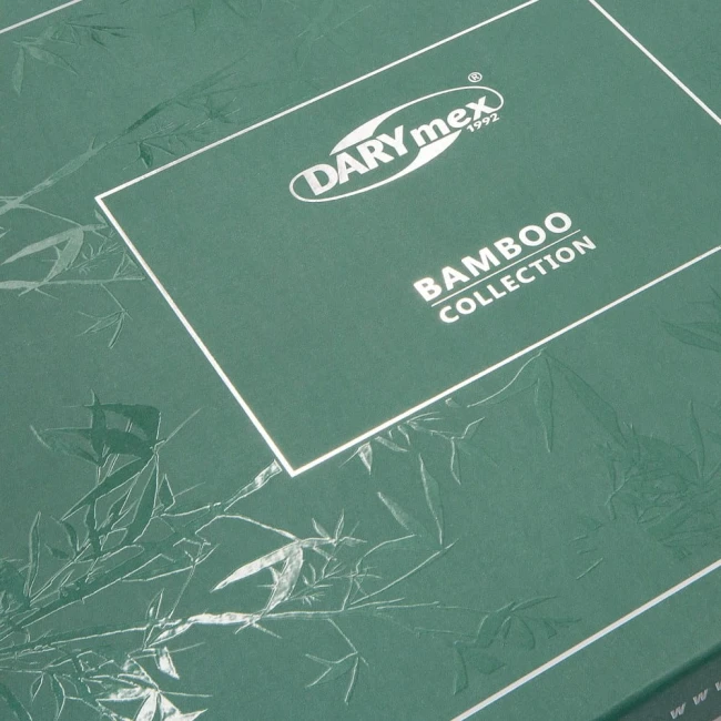 Opakowanie pościeli bambusowej w kolorze ciemnozielonym z białym logo marki DARYmex i napisem BAMBOO COLLECTION. Tło z delikatnym wzorem liści bambusa. Opakowanie leży na płaskiej powierzchni, krawędzie są wyraźnie widoczne.