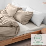 Prześcieradło flanelowe z gumką w kolorze kremowym 160x200, wykonane z materiału o gramaturze 160g/m2. Leży na łóżku, z lekko podwiniętą krawędzią, otoczone białymi poduszkami.