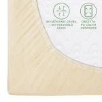 Prześcieradło jersey z gumką 140x200 w kolorze kremowym, leżące na białym tle. Widoczna gruba i wytrzymała guma obszyta po całym obwodzie. Tekstura materiału gładka, delikatna, wyróżnia się estetycznym wykończeniem.