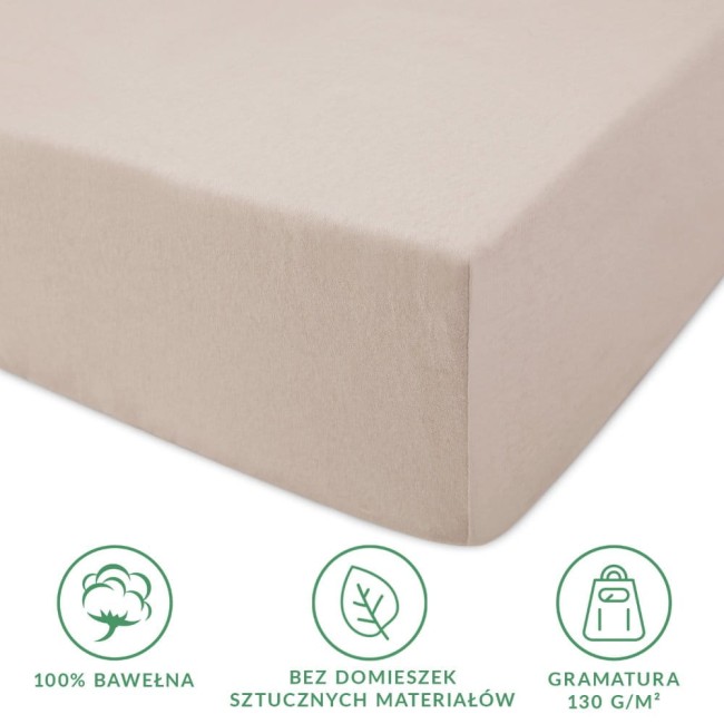 Prześcieradło jersey z gumką 90x200 w kolorze beżowym, wykonane w 100% z bawełny. Zbliżenie na gładką strukturę materiału oraz gumkę, która umożliwia łatwe zakładanie na materac. Gramatura 130 g/m². Bez sztucznych domieszek.