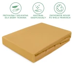 Prześcieradło jersey z gumką 120x200 w kolorze musztardowym, leżące na płaskiej powierzchni. Materiał teksturowany, w pełni rozłożony. Widoczne gumki na rogach zapewniające dopasowanie. Otoczenie neutralne, bez zbędnych elementów.
