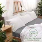 Prześcieradło jersey z gumką 160x200 w kolorze szarym leży na łóżku z widocznym białym pościelą i poduszkami. Kąt ujęcia frontalny, w aranżacji sypialni.