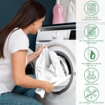 Prześcieradło jersey z gumką 90x200 w kolorze wrzosowym, w rękach osoby wkładanej do pralki. W tle widoczne butelki detergentów. Instrukcje dotyczące prania i pielęgnacji w formie ikon. Produkt leży swobodnie, unika się zagnieceń.