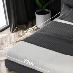 Prześcieradło frotte z gumką w kolorze czekolady, rozmiar 90x200 cm, leży na łóżku. Widoczne wymiary: 200 cm i 90 cm. Materiał o teksturze frotte, dopasowujące się do materaca, umieszczone w jasnej aranżacji. Tło w odcieniach drewna i szarości.