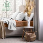 Prześcieradło frotte z gumką 120x200 w kolorze czekoladowym leży na materacu łóżka. Widoczne są poduszki oraz narzuta w jasnym kolorze. Tło to jasna, zdobiona ściana oraz stół z kwiatami w wazonie i koszem.