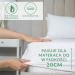 Prześcieradło frotte z gumką w kolorze białym, rozłożone na materacu, pasuje do wysokości 20 cm. W ujęciu z boku widać rękę, która wygładza materiał. Na tkaninie znajdują się czytelne napisy informacyjne: „nie wymaga prasowania” oraz „nie gniecie się”.