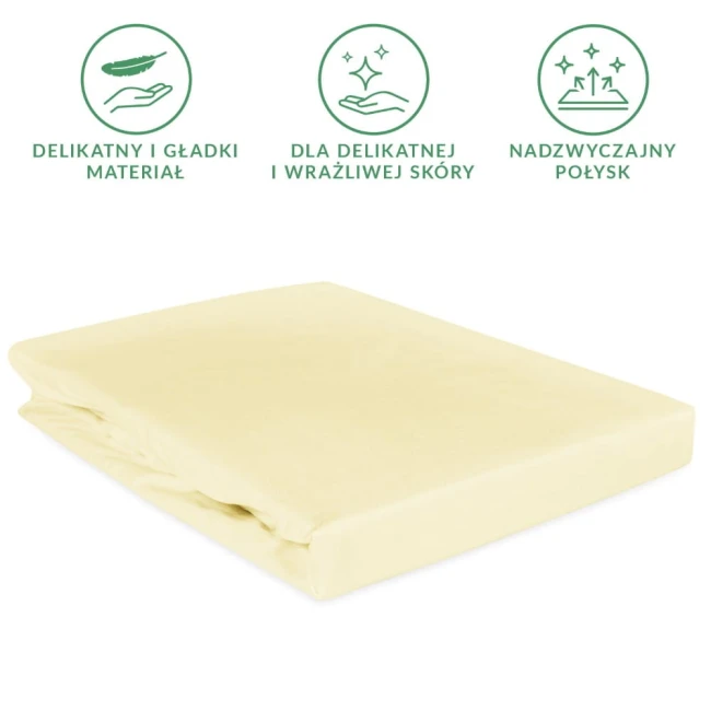Prześcieradło satynowe z gumką w kolorze kremowym, o wymiarach 90x200 cm, leżące na białym tle. Produkt wykonany z delikatnego, gładkiego materiału, idealny dla wrażliwej skóry. Widoczny jest lekki połysk tkaniny.