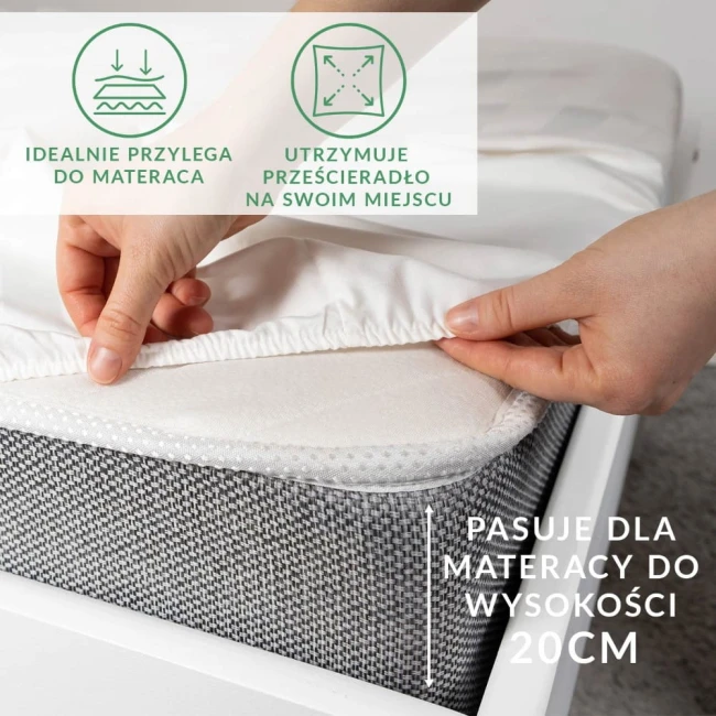 Prześcieradło satynowe z gumką w kolorze kremowym, o wymiarach 200x220 cm, leży na materacu. Widać, że jest elastyczne i dobrze przylega do powierzchni. Widoczna jest struktura materiału oraz tekst informujący o dopasowaniu do materacy o wysokości 20 cm.