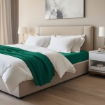Prześcieradło jersey z elastanem w kolorze zielonym, o wymiarach 90x200 cm, rozłożone na łóżku. Widoczne białe poduszki i kołdra, w aranżacji sypialni z jasnymi ścianami i drewnianą podłogą, przy nocnej szafce z lampką.