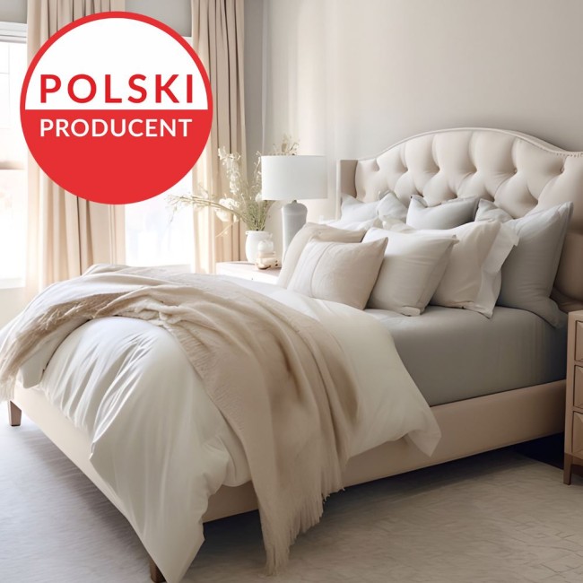 Prześcieradło jersey z elastanem w kolorze różowym, rozmiar 140x200, leżące na łóżku z jasnym topem. W tle widoczna aranżacja sypialni z beżowym wezgłowiem, poduszkami w różnych odcieniach oraz lampką nocną. Obraz skomponowany na neutralnym tle.