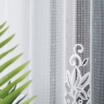 Firana gotowa Berenika w kolorze białym, wykonana z żakardowego materiału, o wymiarach 300x160 cm. Z detalami w postaci wzoru roślinnego. Kompozycja z boku, elementy tła z zielonymi liśćmi roślin. Firana rozłożona, wisząca, z delikatną teksturą.
