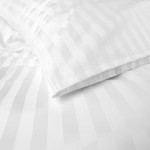 Poszewka na poduszkę 50x60 cm, hotelowa, biała w delikatne, pionowe paski o szerokości 2 cm. Złożona, ujęcie z boku, ukazuje subtelną fakturę materiału. Prosta, jasna aranżacja na jednolitym tle.