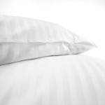 Poszewka na poduszkę hotelową 50x70 cm, biała z delikatnymi, 2 cm paskami, leżąca na gładkim tle. Wykonana z materiału o gładkiej fakturze, z widocznym zamknięciem na zakładkę. Zbliżenie akcentuje detale wzoru.