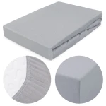 Prześcieradło jersey z gumką 120x200 w kolorze popielatym, leżące na płasko. Zbliżenie na detal gumki i krawędzi, ukazujące fakturę materiału. Proste, jednolite tło. Idealne dla materacy o wymiarach 120x200 cm.