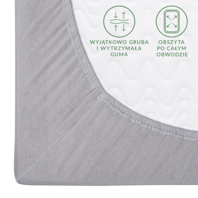 Prześcieradło jersey z gumką 160x200 w kolorze popielatym, z bliska na krawędzi. Widoczna gruba, elastyczna guma na całym obwodzie, materiał o teksturze dzianiny. Na białym tle widać napisy informacyjne dotyczące gumy.