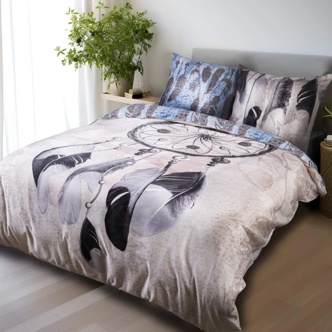 Pościel satyna bawełniana 140x200 w kolorze fioletowo-różowym, z wzorem łapacza snów i piór. Rozłożona na łóżku, widoczna faktura materiału. W zestawie poszewki na poduszki z podobnym wzorem. Tło jasne, z elementami zieleni roślinnej.