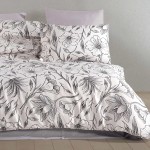 Pościel satyna bawełniana 160x200 w kolorze białym z czarnym konturowym wzorem kwiatów i liści. Widok frontalny, produkt rozłożony na łóżku z dwoma poduszkami. Gładka, satynowa faktura materiału sprawia, że wygląda elegancko i stylowo.