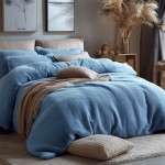 Pościel frotte 160x200 w kolorze błękitnym, złożona i rozłożona na łóżku. W tle poduszki w odcieniach błękitu oraz beżu. Dekoracje w postaci suchych roślin i obrazów na ścianie. Ujęcie z boku, na jasnym tle.