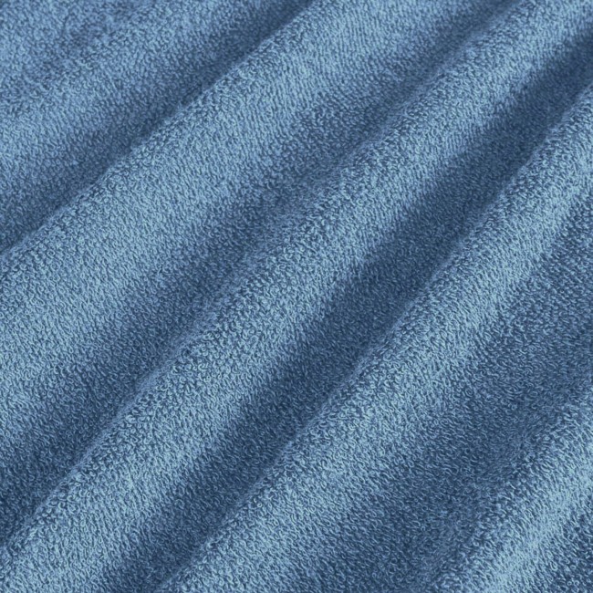 Pościel frotte 160x200 w kolorze błękitnym, z teksturowanej tkaniny o delikatnym, miękkim wykończeniu. Ułożona w lekkie fałdy, podkreślająca fakturę materiału. Zdjęcie zbliżeniowe, ukazujące detale i kolorystykę produktu.