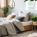 Prześcieradło flanelowe z gumką w kolorze jasnego beżu, o wymiarach 120x200 cm, złożone na łóżku z poduszkami w odcieniach szarości i beżu. Otoczone roślinnością oraz lampką. Tło w neutralnych pastelach. Widać fakturę materiału.
