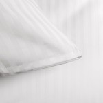 Pościel hotelowa bawełniana 220x200 cm w białe pasy 1 cm, z zakładką 30 cm. Ujęcie w zbliżeniu na krawędź poszewki, ukazujące delikatną fakturę materiału i wykończenie. Proste, białe tło podkreśla wzór, bez dodatkowych dekoracji.