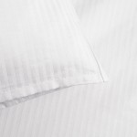 Pościel hotelowa bawełniana 160x200 w pasy 4-mm biała na zakładkę 30 cm, nawiązująca do eleganckiego wystroju. Widok z bliska, pokazujący detale faktury i wzoru, z poduszką w pasy leżącą na płaskiej powierzchni.