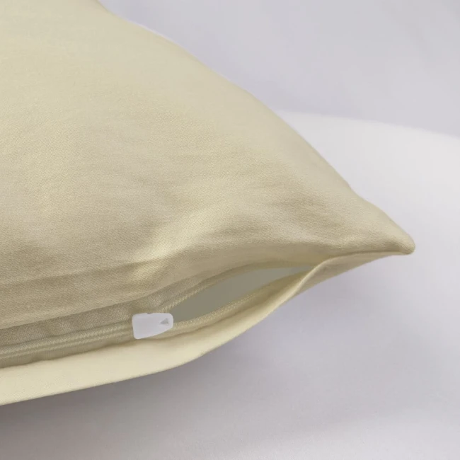 Poszewka satynowa 70x80 w kolorze kremowym, leżąca na jasnym tle, z widocznym zamkiem błyskawicznym. Materiał gładki, z delikatnym połyskiem, podkreślający elegancki wygląd. Odpowiednia do poduszki o wymiarach 70x80 cm.